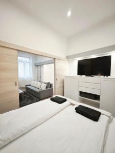 ein weißes Zimmer mit einem großen Bett und einem Sofa in der Unterkunft Vibe City Apartment in Kecskemét