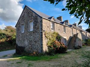 an old brick building with stairs and flowers at La Mainerie in Jobourg