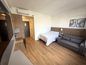 ein Hotelzimmer mit einem Bett und einer Couch in der Unterkunft Stay Inn com Vista Mar Parcial, Piscina, opção de estacionamento na quadra da praia in Santos + 12 Fotos