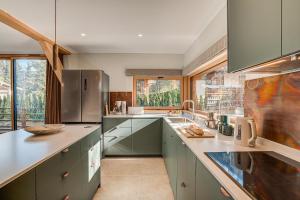 une cuisine avec des placards verts et une grande fenêtre dans l'établissement Chalet Diard, Detached Chalet, Alpes Travel, Sleeps 6 to 8, à Chamonix-Mont-Blanc