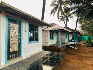 une petite maison avec une porte et des palmiers dans l'établissement Sukhi Beach Cottage, à Gokarna 14 autres photos