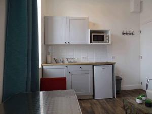 een kleine keuken met witte kasten en een tafel bij Marc1 in Saint-Valéry-en-Caux