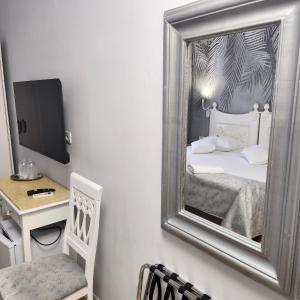 a mirror in a room with a bed and a desk at Hotel Mantra in Arad