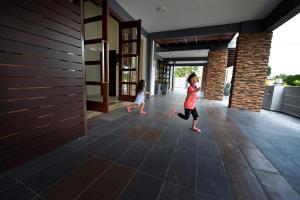 dos niños caminando en el pasillo de una casa en Palm City Villa en Kuantan