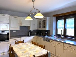 Una cocina con gabinetes blancos y una mesa con sillas. en Gite d'arnaud & emilie, en Deville