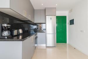 une cuisine avec des armoires blanches et une porte verte dans l'établissement Sea View Monteparaiso, à Puerto Rico