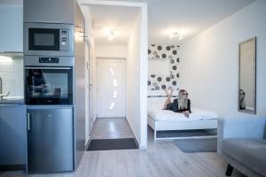 een man zit op een bed in een kamer bij Antracit Apartman - free parking in Pécs