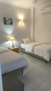 a bedroom with two beds and a lamp on a table at Maat apartment in Luxor