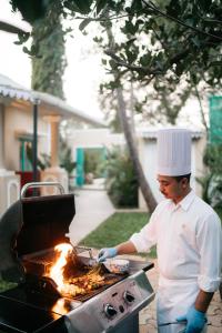 Ein Mann, der mit Flammen Essen auf einem Grill kocht in der Unterkunft amã Stays & Trails - Assa 360 , Goa in Assagao
