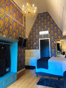 a bedroom with a blue bed and a chandelier at Hotel Villa Verde - by Easy Hotéis in São Bento do Sul