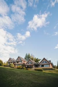 a row of houses on a green lawn with a cloudy sky at Hosteria CuyenCO in Villa La Angostura +13 photos