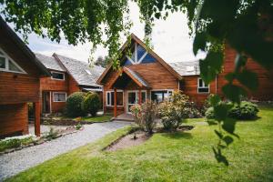 a wooden house with a garden in front of it at Hosteria CuyenCO in Villa La Angostura