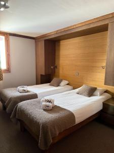 two beds in a hotel room with towels on them at Résidence Montana Caron by Village Montana in Val Thorens
