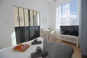 a bedroom with a bed with a television and a table at La Campus Douillet in Saint-Étienne