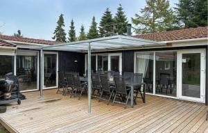 a patio with a table and chairs on a deck at Awesome Home In Væggerløse With Sauna in Marielyst +9 photos