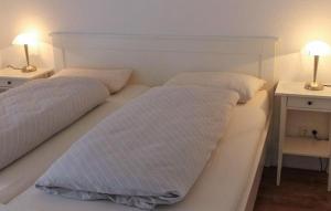 2 bedden met witte lakens en kussens in een slaapkamer bij K104 Eg in Marienfelde +2 foto's