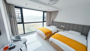 Una habitación de hotel con dos camas y una ventana. en Zhangjiajie Qingfeng B&B West Station Branch, en Zhangjiajie