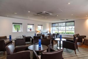 a waiting room with tables and chairs at Holiday Inn Express Glasgow Airport by IHG in Paisley