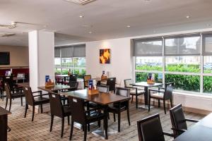 a dining room with tables and chairs and windows at Holiday Inn Express Glasgow Airport by IHG in Paisley