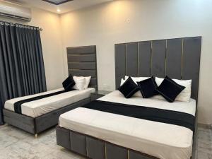 zwei Betten in einem Hotelzimmer mit schwarzen und weißen Kissen in der Unterkunft BNB Royal Galaxy Family Hotel in Karatschi
