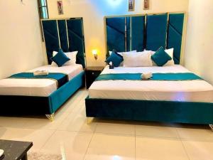 2 Betten in einem blau-weißen Zimmer in der Unterkunft BNB Royal Galaxy Family Hotel in Karatschi