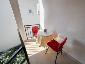 een tafel en twee rode stoelen op een balkon bij Apartments Adna in Podaca