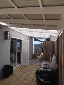 a living room with a black couch on a wooden deck at Melkbos Sea Spray Studio Apartment in Cape Town