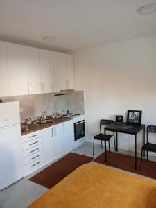 eine Küche mit weißen Schränken und einem Tisch mit Stühlen in der Unterkunft Boki in Belgrad
