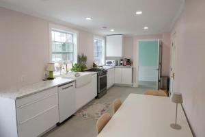 a kitchen with white cabinets and a table with chairs at Bosch Huse Rosé - Zomer in Savannah