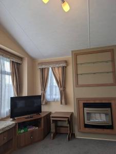 Una sala de estar con televisión y chimenea. en Camber Sands Holiday Park, en Camber