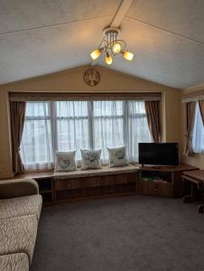 Una sala de estar con un sofá y una ventana grande. en Camber Sands Holiday Park, en Camber