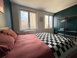 ein Schlafzimmer mit einem karierten Bett und zwei Fenstern in der Unterkunft Appartement Pop et coloré au coeur de Dunkerque in Dunkerque