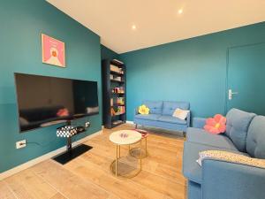 ein Wohnzimmer mit einem blauen Sofa und einem Fernseher in der Unterkunft Appartement Pop et coloré au coeur de Dunkerque in Dunkerque