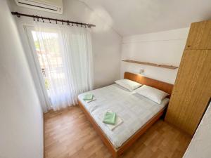 een kleine slaapkamer met een bed en een raam bij Apartments Adna in Podaca