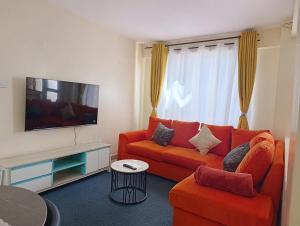 a living room with a orange couch and a flat screen tv at Luxe one bedroom Kikuyu in Kikuyu