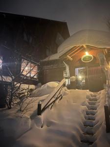a snow covered building with a sign on it at Heidi Guest House in Yuzawa
