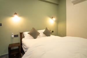 a bedroom with a white bed with two pillows at Ahrin House-entire villa with kitchen and parking in Dharmsala