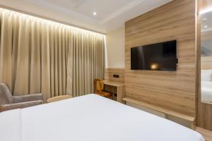 a hotel room with a bed and a flat screen tv at Monday Premium Madhapur in Hyderabad