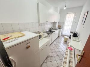 een keuken met witte apparatuur en een witte tegelvloer bij Apartments Adna in Podaca