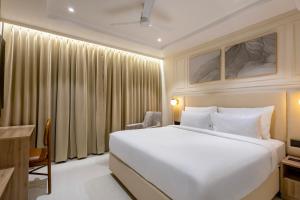 a bedroom with a large white bed and a chair at Monday Premium Madhapur in Hyderabad