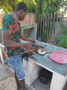 a man cooking food on top of a grill at Villa Ilo Komba in Ampangorinana