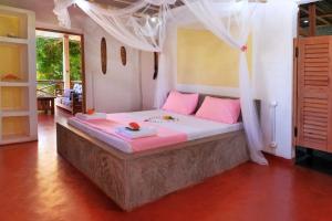 a bedroom with a large bed with pink pillows at Villa Ilo Komba in Ampangorinana