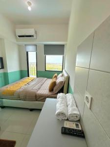 a bedroom with a bed and a desk with a remote control at Apartemen OSAKA Riverview PIK2 Studio By GPI in Rawalumpang +8 photos