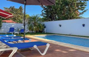 einen Pool mit blauen Stühlen und einem Sonnenschirm in der Unterkunft Gorgeous Home In Chiclana De La Fronter in Chiclana de la Frontera