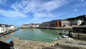 a river in a city with buildings and houses at Marc 2 in Saint-Valery-en-Caux