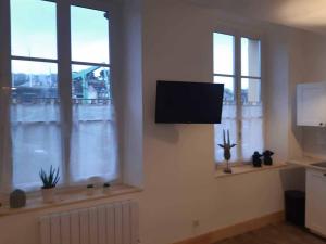 a living room with two windows and a flat screen tv at Marc 2 in Saint-Valery-en-Caux