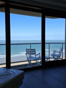 a room with a view of the ocean and two chairs at LUXURY APP, frontal sea View + south terrace + garage in Middelkerke