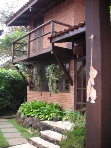 a brick house with a balcony and a garden at Recanto Marazul in Ubatuba