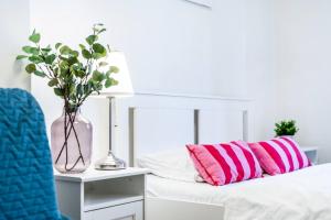 a white bed with pink and pink pillows and a lamp at 2BDR Old Town Square Apartments w Fast Wi-Fi in Prague