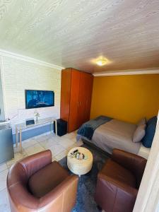 a bedroom with a bed and two chairs and a tv at Honey Crib at Waterfall East in Rustenburg